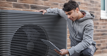 Image of someone infront of a heat pump